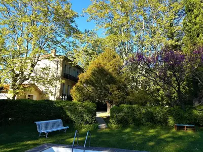 a park bench sitting in the grass in front of a building at Embarben Maison d'hôtes in Saint-Chamas
