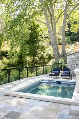 a swimming pool with two chairs and a fence at Les Cabanes de la Fontaine in Lacoste