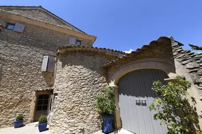 a large stone building with a white garage door at Bastide Des Demoiselles in Roussillon