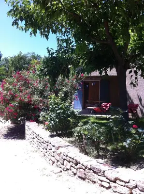 a house with a stone wall and flowers at Gardiole in Bonnieux