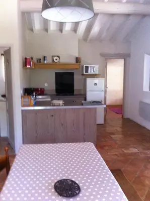 a room with a table and a kitchen with a counter at Gardiole in Bonnieux