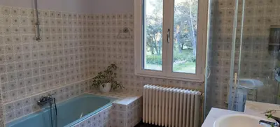 a bathroom with a tub and a sink and a window at Loue haut de villa au calme piscine jardin arboré in Cornillon-Confoux