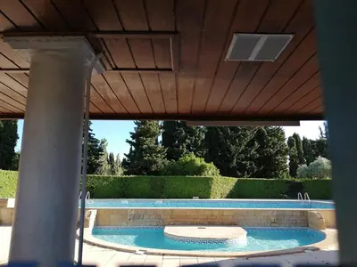a large swimming pool with a wooden ceiling and a pool at La perle des Alpilles Résidence les MYRTILLES in Eyguières