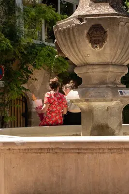 two women drinking water from a fountain at Les Maisons Mado in Venasque