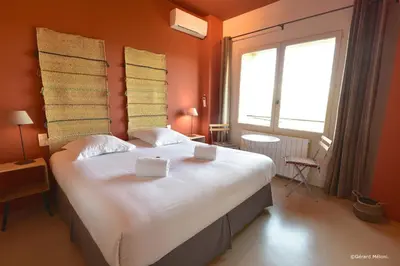 a bedroom with a large white bed with orange walls at Les Maisons Mado in Venasque