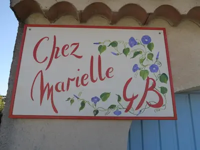 a sign on the side of a building with flowers at Chez Marielle in LʼIsle-sur-la-Sorgue
