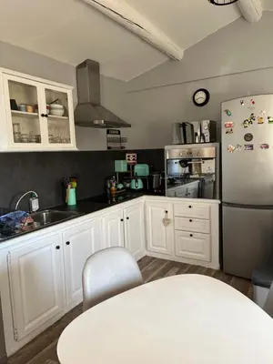a kitchen with white cabinets and a white refrigerator at Appartement St Victor in Puyvert