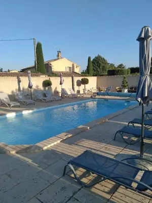 a swimming pool with lounge chairs and an umbrella at DANSAVAN Chambres d Hôtes Gite in Oppède