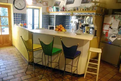 a kitchen with a counter with chairs and a refrigerator at Les Volets Bleus Provence in Salon-de-Provence