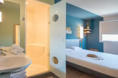 a small room with two beds and a mirror at ibis budget Pertuis Portes du Luberon in Pertuis
