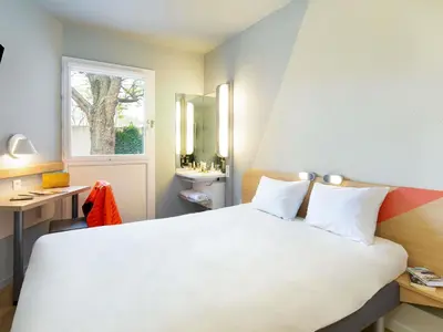 a bedroom with a large white bed and a window at ibis budget Cavaillon in Cavaillon