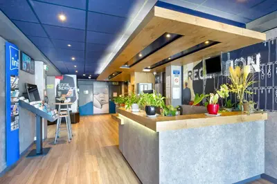 a lobby with a counter with potted plants at ibis budget Cavaillon in Cavaillon