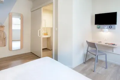 a bedroom with a bed and a desk and a tv at ibis budget Cavaillon in Cavaillon