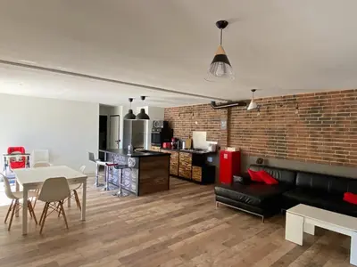 a living room with a black couch and a brick wall at Maison dans quartier calme in LʼIsle-sur-la-Sorgue