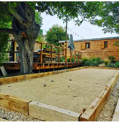 a backyard with a tree and a building at Roulotte la clé du Luberon in Buoux