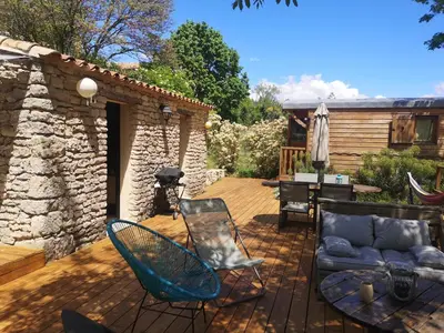 a patio with chairs and a couch and a grill at Roulotte la clé du Luberon in Buoux