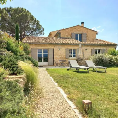a house with two benches in front of a yard at Le Cottage du Chat Blanc in Saint-Didier