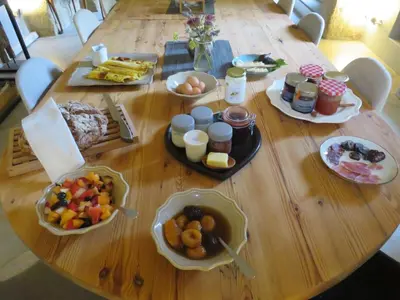 a wooden table with many plates of food on it at Maison Lou Roucas in Cabrières-dʼAigues