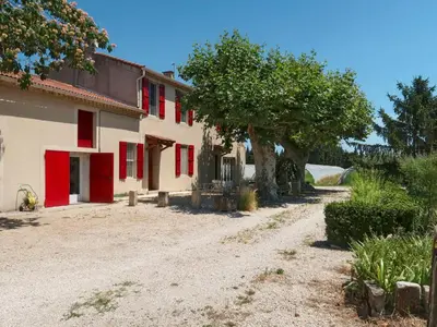 a house with red shutters and a tree next to a dirt road at Holiday Home Mas de la Gourmette by Interhome in Châteaurenard