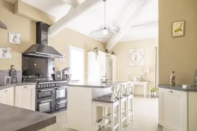 a kitchen with white cabinets and a island with bar stools at Villa Mireillo in Noves