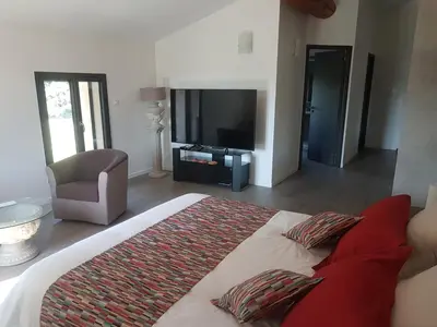 a bedroom with a bed with a television and a chair at Mas Des Fugueyrolles in Cavaillon