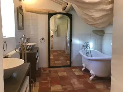 a bathroom with a tub and two sinks and a mirror at Le mas jasmins in Ménerbes
