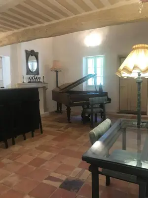 a living room with a piano and a table at Le mas jasmins in Ménerbes