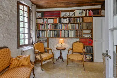 a library with chairs and a table and books at Santonne in Apt