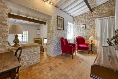 a room with two red chairs and a stone wall at Santonne in Apt