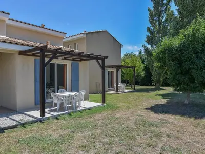 a patio with a table and chairs in a yard at Residence Sun Hols Les Rives du Lac in Saint-Saturnin-lès-Avignon