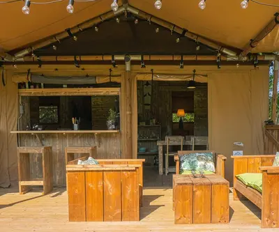 a patio with a tent with a table and a chair at Lodge St Exupéry in Le Thor