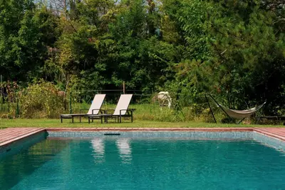two chairs and a hammock next to a swimming pool at Lodge St Exupéry in Le Thor
