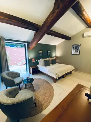 a bedroom with a bed and a large window at Hôtel le Jas de Joucas in Joucas