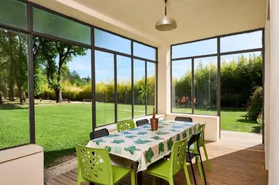 a dining room with a table and chairs and large windows at La Velleronnaise in Velleron