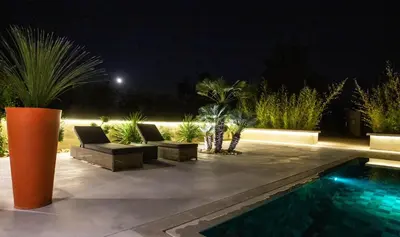 a patio with chairs and a swimming pool at night at VILLA PALMA & SPA in LʼIsle-sur-la-Sorgue
