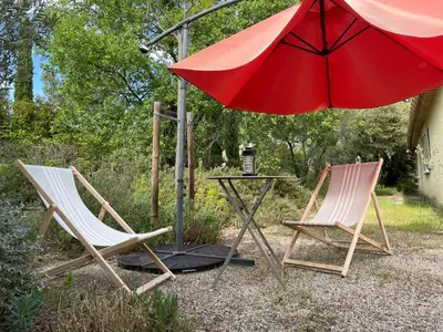 two chairs and a table with an umbrella at Studio Idéal pour des moments d'exceptions in Cabrières-dʼAvignon