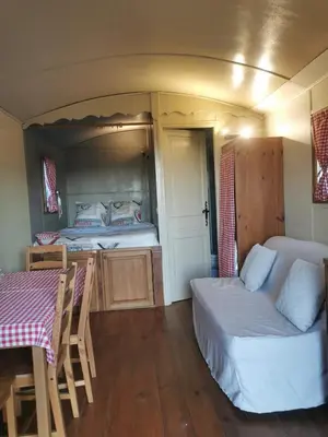 a room with two beds and a table and a table and chairs at La Carriole dans le jardin in Ménerbes