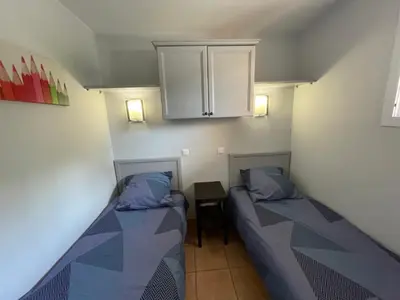 two beds in a room with a cabinet and a table at Studio sur le Domaine du Golf de Pont Royal in Mallemort