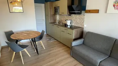 a living room with a table and a couch and a kitchen at Studio sur le Domaine du Golf de Pont Royal in Mallemort