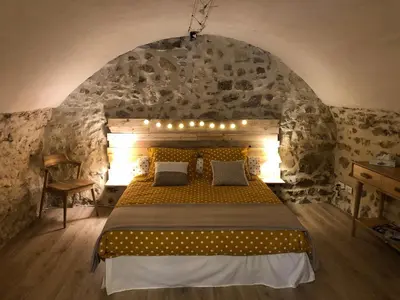 a bedroom with a large bed in a stone wall at L'Atelier de Marie in Eyguières