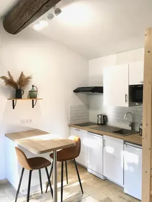 a kitchen with white cabinets and a wooden table at Mazet LEAJO in Eygalières