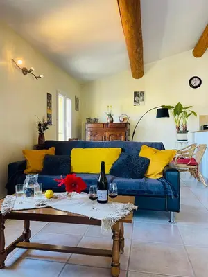 a living room with a blue couch and yellow pillows at Gîte Les Vignes in Carpentras