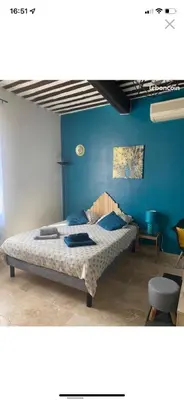a bedroom with a bed with a blue wall at Studio de charme le Clos de l'Etang + place de parking in LʼIsle-sur-la-Sorgue