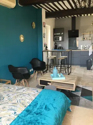 a room with a bed and a kitchen with chairs at Studio de charme le Clos de l'Etang + place de parking in LʼIsle-sur-la-Sorgue