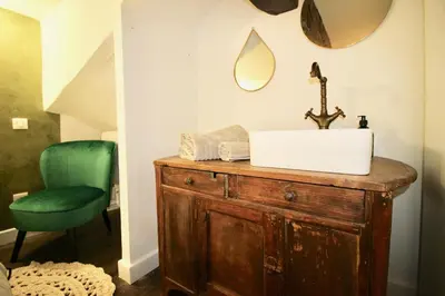 a bathroom with a sink and a green chair at Le Madeleine (duplex) in Aix-en-Provence