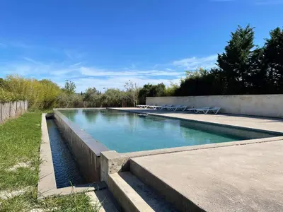 a swimming pool with blue water in a yard at Appartement de charme Sud Luberon classé 4 étoiles in Puyvert
