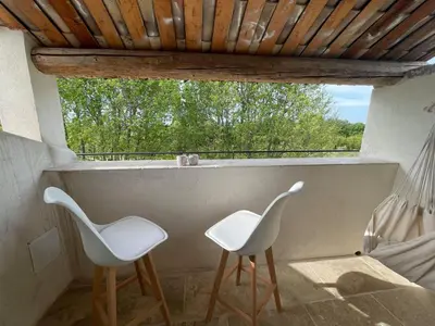 two white chairs sitting on a balcony with a window at Appartement de charme Sud Luberon classé 4 étoiles in Puyvert