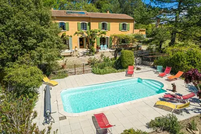 an outdoor swimming pool with chairs and a house at Mas de Bacalan in Mormoiron