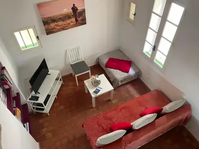 a living room with a red couch and a tv at Studio cosy dans le centre-ville historique in LʼIsle-sur-la-Sorgue