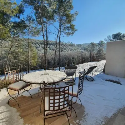 a table and chairs on a patio with snow on it at Le Vallon des Pins in La Cride